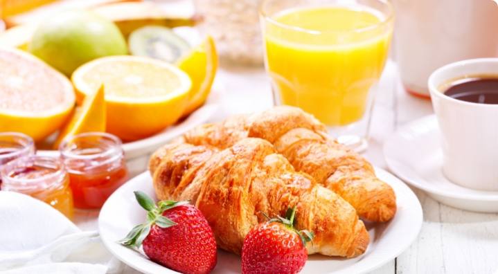 des croissants, des fruits, de la confiture, du jus d'orange disposé sur une table